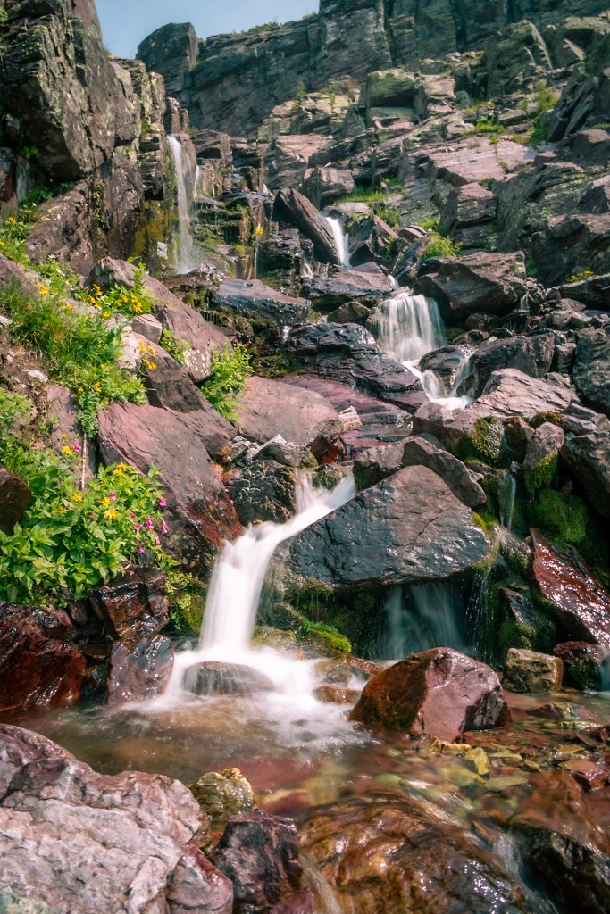 A waterfall cascades down a rocky slope, changing directions several times.