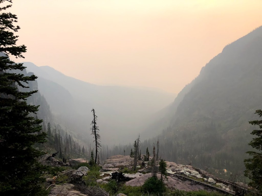 A view down through a mountain valley so thick with smoke that very little detail can be seen.