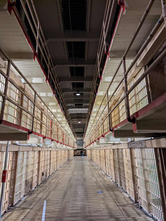 The same triple-high row of cells, now with dark skylights above and the light from inside the cells glowing white. There are no people in the frame.