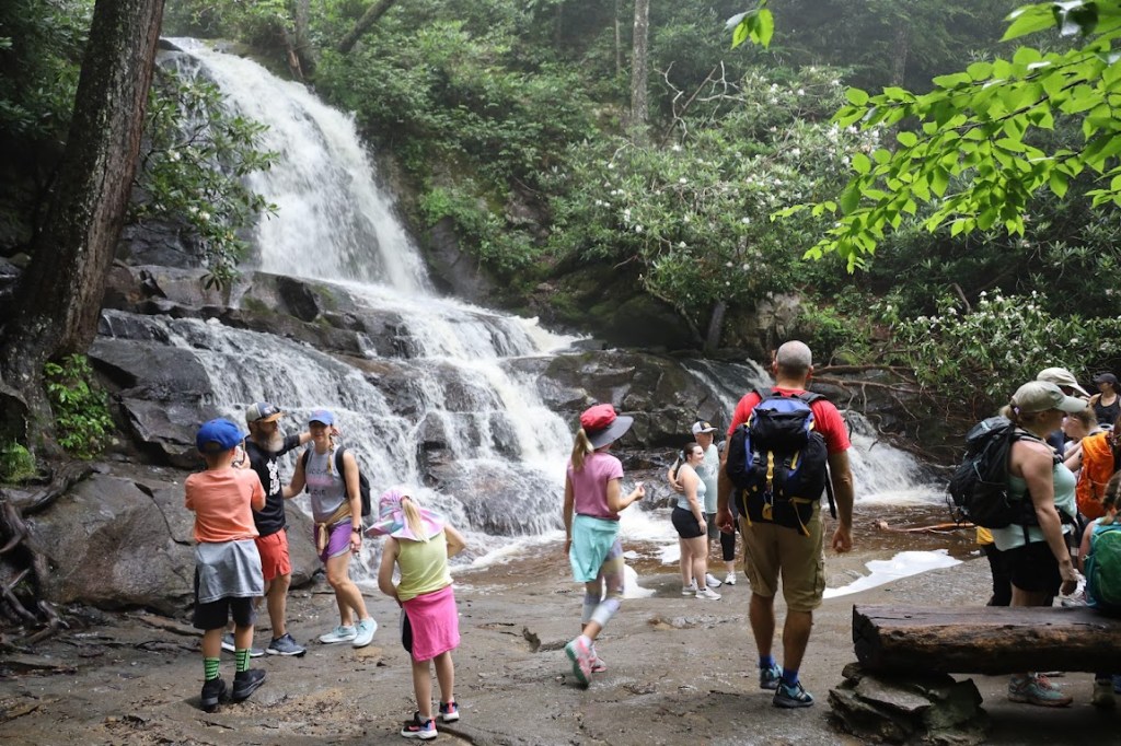 A crowd moves around in front of the same waterfall. 