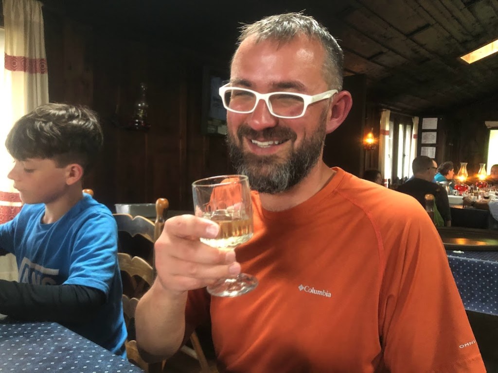 Dustin smiles over a glass of white wine. 