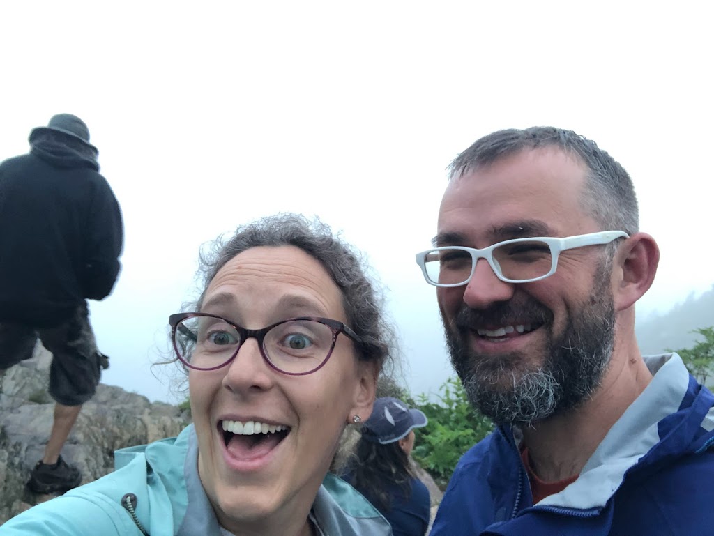 Selfie of Laura and Dustin in front of an all-gray background.
