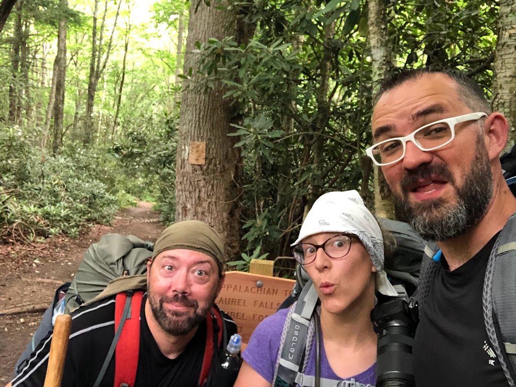 A selfie with Hobz at left, Laura center, Dustin right. A sign with the words "Appalachian Trail" barely visible is in the background, along with a path stretching back into the woods.