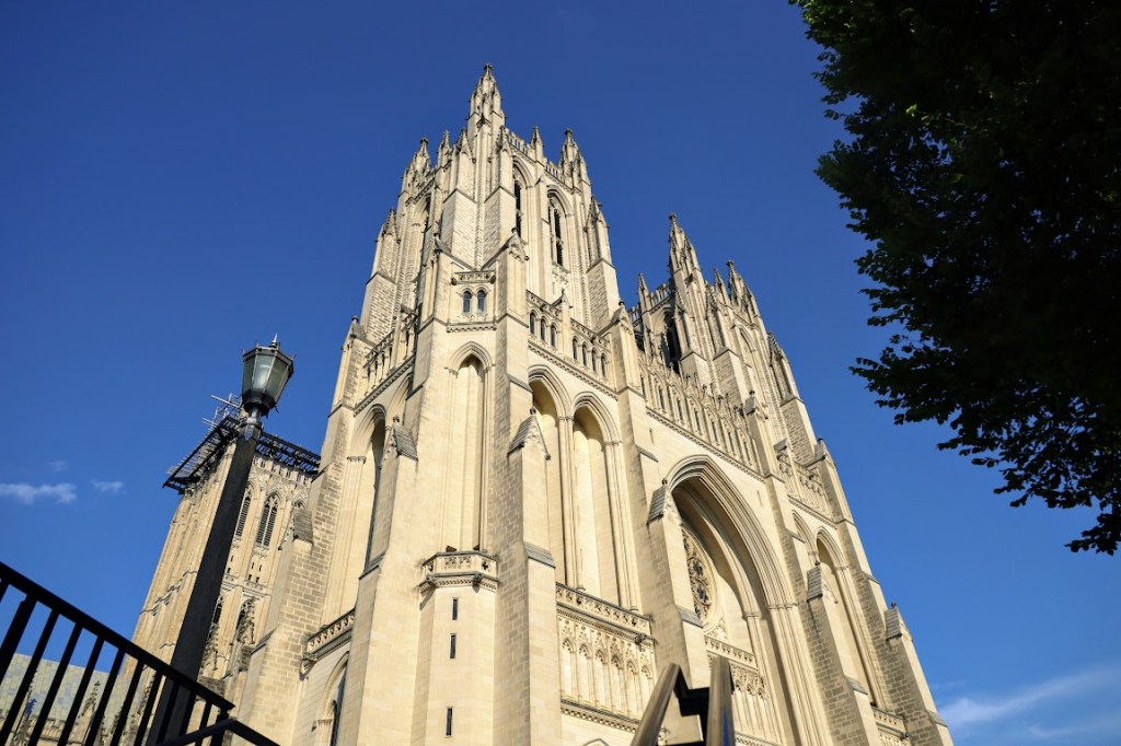 The west facade of the National Cathedral fills the frame against a bright blue sky.