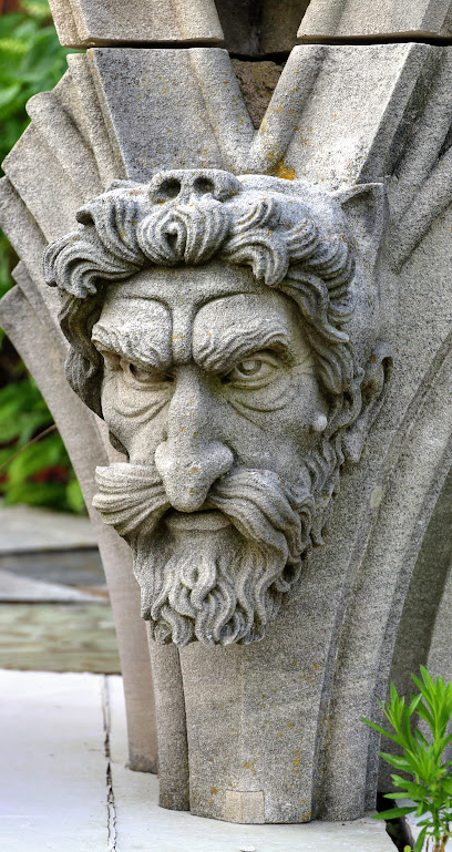 A cathedral grotesque featuring the face of a bearded man with an extremely impressive mustache and maybe cat ears?