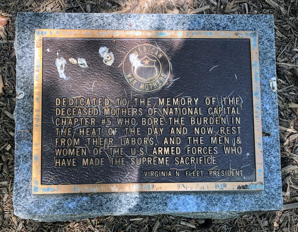 A bronze plaque set on a granite stone. The inscription reads: 

Dedicated to the memory of the deceased mothers of national capital chapter #5 who bore the burden in the heat of the day and now rest from their labors, and the men & women of the U.S. Armed Forces who have made the supreme sacrifice.