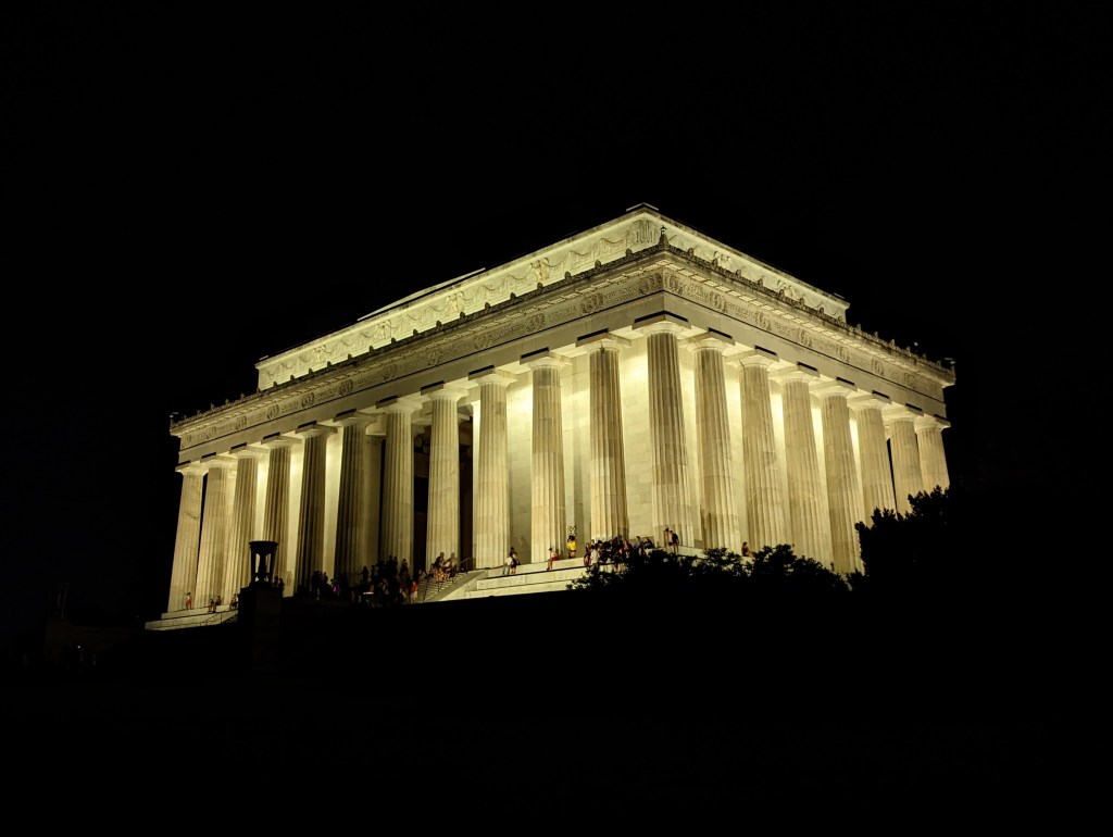 The Lincoln Memorial glows white in the center of the night time photo. All other scenery is completely black, so that the memorial appears to be floating.