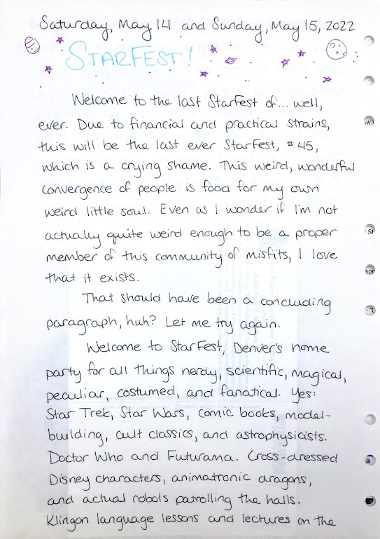 A photograph of a hand-written journal page. The heading is written in turquoise ink with purple stars, moons, and planets doodled around it. One of the planets looks like an easter egg, but is probably meant to be Jupiter.