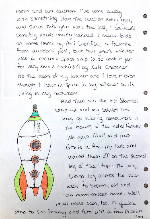 A photograph of a hand-written journal page. The handwriting is in black ink. A cartoon-style sketch of a rocket ship labeled "DUBHE" is on the bottom left.