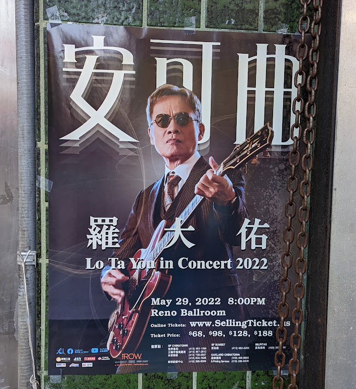 A poster for "Lo Ta You in Concert 2022" depicting a Chinese wearing sunglasses, a suit, and entire boatloads of gravitas playing a guitar.