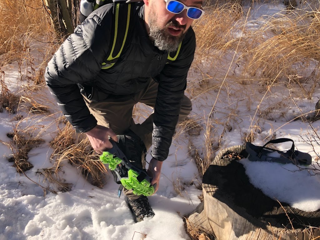 A closeup of Dustin pulling on microspikes over his boots. 
