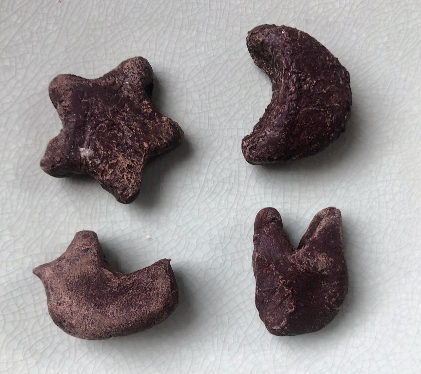 A closeup of four shapes formed from cacao paste: star, moon, chick, and bunny-probably.